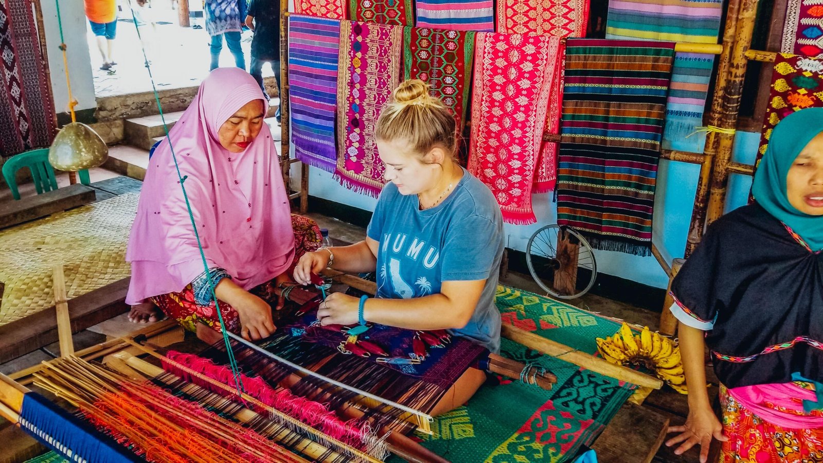 Tourist learning traditional Sasak weaving with a local artisan in Lombok